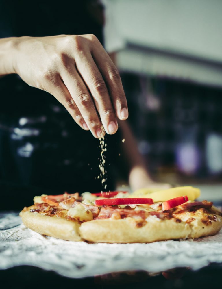 Close up of woman hand putting oregano over tomato and mozzarell